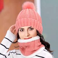 Mulher de blusa branca de listas com gorro e cachecol rosa
